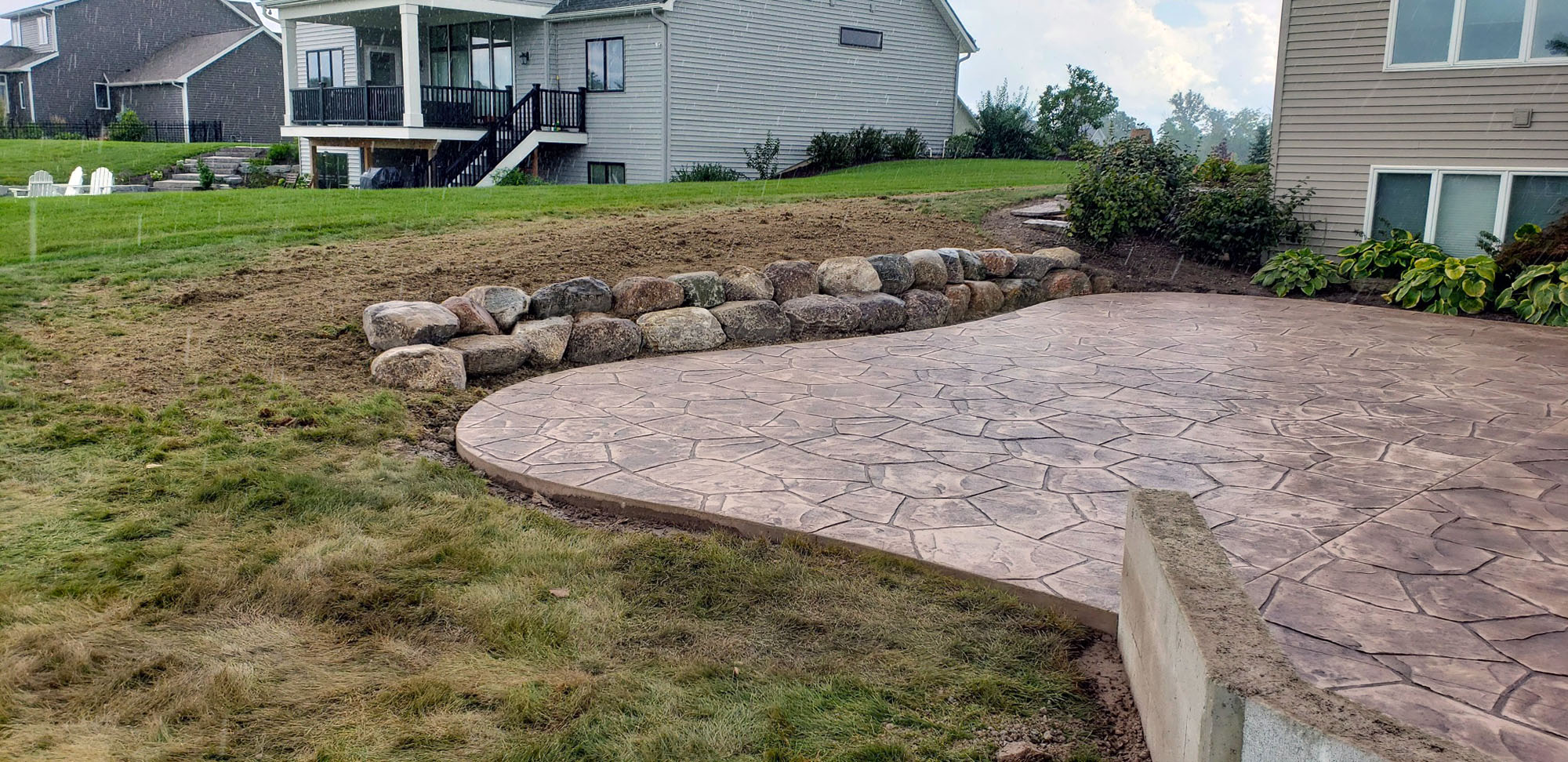 freshly poured stamped concrete back yard patio with boulder retaining wall freshly poured stamped concrete back yard patio with boulder retaining wall