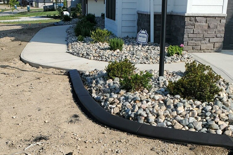 view of newly landscaped front driveway featuring white stone and concrete edging view of newly landscaped front driveway featuring white stone and concrete edging