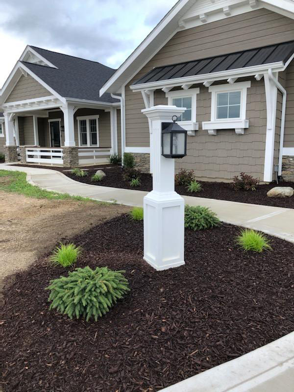 front view of a gray home with new landscaping that features brown mulch and green shrubs front view of a gray home with new landscaping that features brown mulch and green shrubs