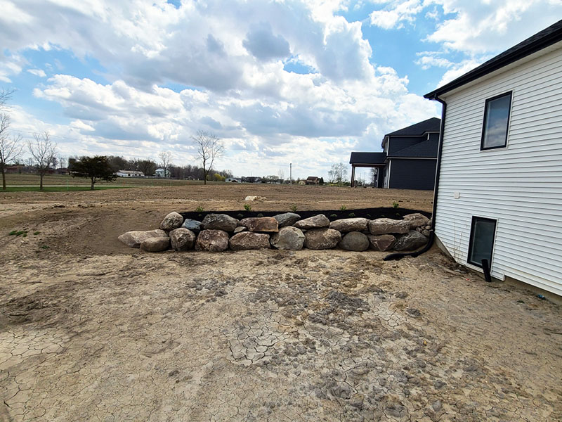 view of backyard with landscape rock retaining wall consisting of large boulders view of backyard with landscape rock retaining wall consisting of large boulders